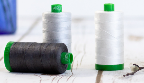 3 Aurifil 40 weight thread spools in neutral colours
