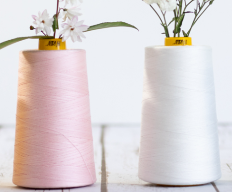 2 cones of Aurifil Forty3 longarm thread cones in pink and white with flowers